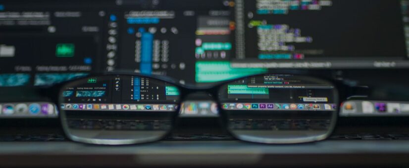 Glasses resting in front of a darkened screen of code