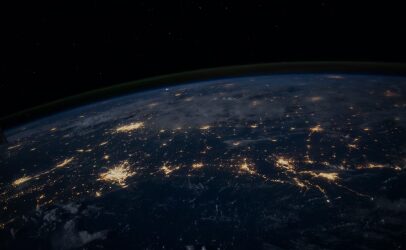 The Earth at night from orbit, city lights tracing the coastlines